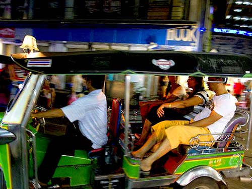 Tuk-tuk with tourists Bangkok downtown at night.