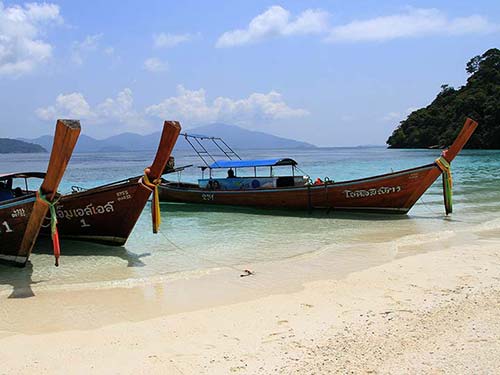 Long-tail boats stranded in a tropical beach.